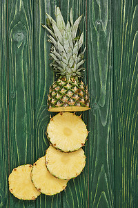 美味菠萝摄影照片_在绿色木桌上看到美味菠萝切片圈的顶视图