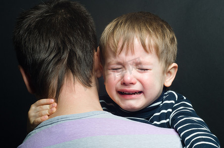哭泣摄影照片_在爸爸的怀里哭泣的孩子