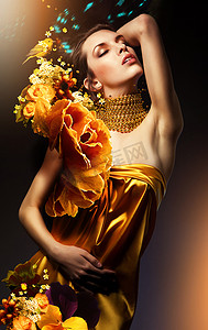 有魅力的女人在黄色礼服与首饰和鲜花