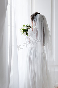 在婚纱礼服与传统的面纱和花束的黑发新娘的背面视图 