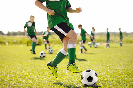 草地上的男孩跑得快，跳跃和踢球。足球训练队。青少年足球队训练夏令营