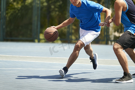 年轻的亚洲成人球员在户外球场打篮球.