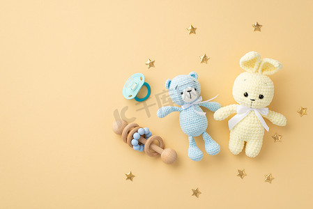 婴儿用品概念。针织兔子玩具、玩具玩具、木制响尾蛇、蓝色奶嘴、金色星辰的全景照片。