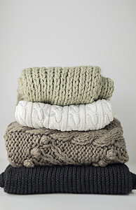 暖羊毛针织冬秋季的衣服, 叠成一堆在一张白纸上。毛衣围巾文本的位置。Copyspace.