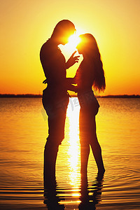 在海滩上的情侣剪影。夕阳的光辉
