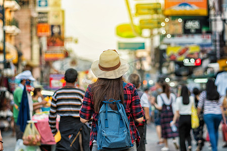 年轻的亚洲旅行妇女的背面步行和看在考山路步行街在晚上在泰国曼谷, 旅行者和旅游概念