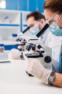 科学家在医学面具和护目镜中的选择性聚焦实验室中的董事看显微镜