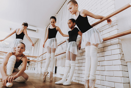 可爱芭蕾摄影照片_室内年轻女孩团体的芭蕾培训。古典芭蕾。巴莱丽娜·图图的女孩。室内训练。可爱的舞者大厅里的表演。舞蹈练习。穿白色衣服的女孩.