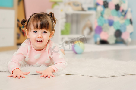 玩玩具的小女孩摄影照片_可爱快乐 2 岁小女孩玩玩具在家里。Pastele 音调，早期学习概念的现代幼儿园室内