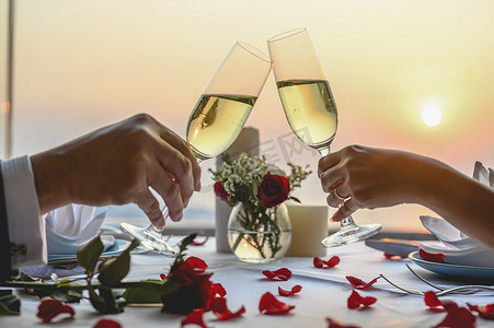 夕阳西下的餐厅里,情侣们一起享受着一杯干杯的美酒.情人节，情侣，蜜月，晚餐，酒，浪漫的概念. 