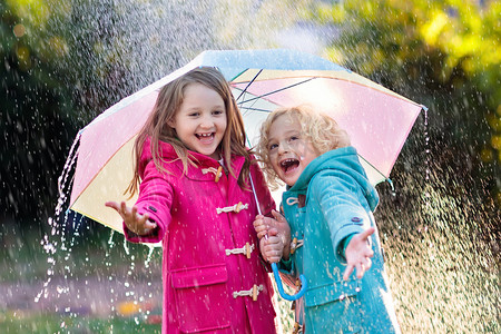 带雨伞的孩子在秋阵雨中玩耍.