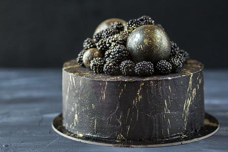 深色背景下的黑饼.万圣节的蛋糕。一个装饰着黑莓和金球的派。带有浆果的节庆甜点.