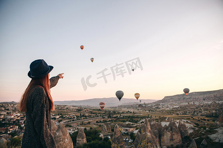 一个戴着帽子的旅游女孩羡慕在土耳其上空飘扬的热气球。令人印象深刻的景象.
