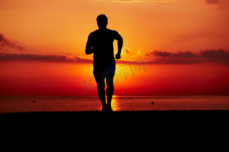 在橘红色的日出，男运动员与肌肉发达的身体，在早上慢跑、 有吸引力慢跑者在行动、 健身和健康的生活方式的概念对海滩上慢跑运动转轮的剪影