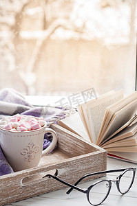 书翻开摄影照片_咖啡杯、 翻开的书、 眼镜、 棉花糖和格子冬季的窗台上。概念温暖和舒适的家居装饰