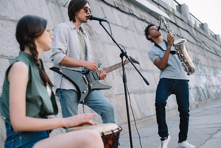 街头音乐家乐队演奏吉他, 鼓和萨克斯在阳光明媚的城市街道上