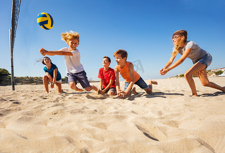 防风少年摄影照片_在沙滩排球比赛中与朋友们一起碰撞传球的快乐少年肖像
