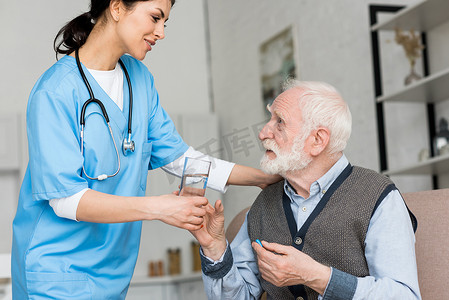 护士给老人杯水, 手里拿着药丸