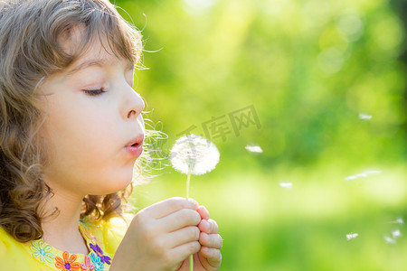 蒲公英摄影照片_快乐的孩子在户外吹蒲公英的花