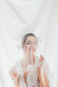 布吕内特新娘穿着婚纱,靠近白布,触摸花边面纱 