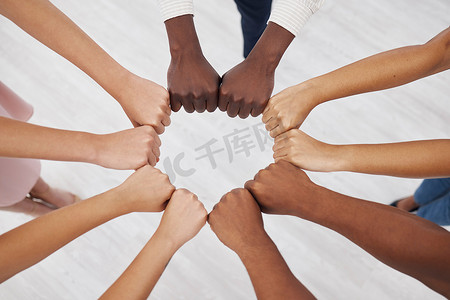 Closeup of a group of businesspeople giving each other a fist bump together in an office at work. Business professionals having fun standing with their fists together for support and motivation during