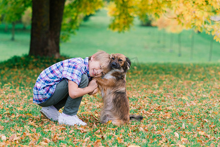 可爱的男孩和他的狗在草地上玩耍和散步.