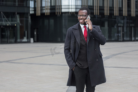 英俊深色皮肤的非洲商人的水平照片在街上, 在他的方式, 从或商务会议, 讨论与客户或同事在电话的重要问题