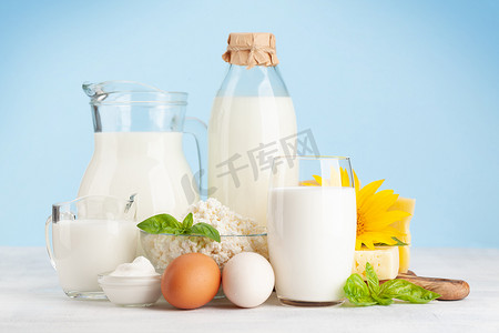 蓝色背景摄影照片_各种乳制品。牛奶，奶酪，农舍，酸奶油。在蓝色背景的前面