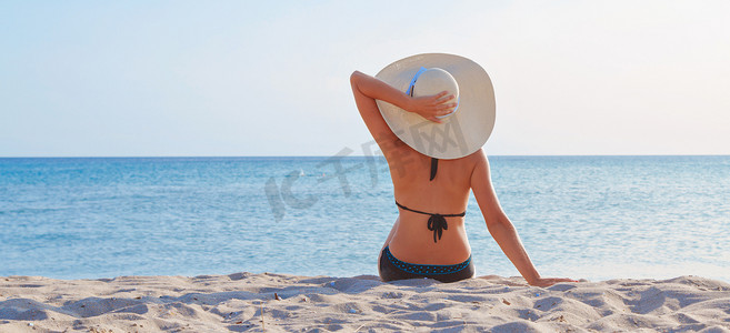 去大海的旅程。穿着泳衣，戴着帽子，在海滩上晒日光浴的女孩。坐在沙滩上的游客。休闲装。复制空间