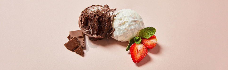 白色冰淇淋球摄影照片_新鲜美味的白色和巧克力冰淇淋球的顶部视图，带有薄荷和草莓粉红背景，全景镜头