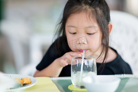 使用稻草从玻璃的亚洲孩子喝水
