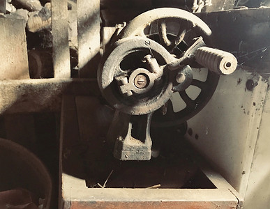 手工驱动旧缝纫机特写。覆盖着腐蚀, 灰尘和蜘蛛网。在一个木制废弃的谷仓的背景下.
