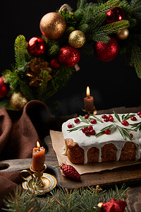 传统的圣诞蛋糕，在圣诞花环附近有覆盆子和蜡烛，放在木制桌子上，与黑色隔离