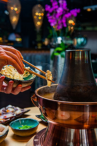 拿着照片摄影照片_拿着筷子在传统的亚洲火锅里做饭的人的剪下来的照片