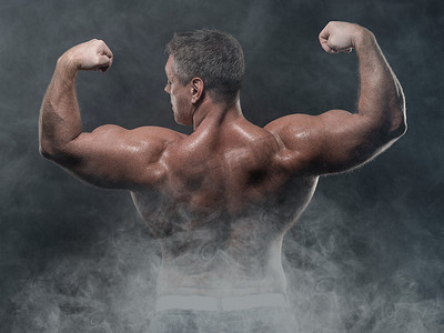 一个强壮的肌肉男在黑色背景下显示二头肌。力量与健身理念
