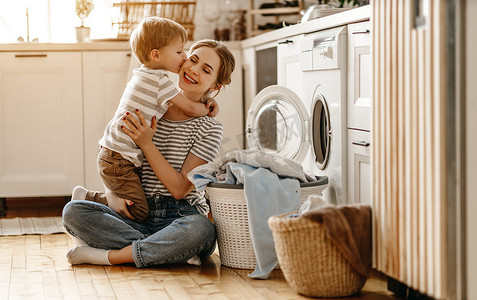 快乐的家庭母亲、家庭主妇和孩子都在洗衣机里洗衣服