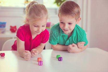 骰子摄影照片_两个快乐的孩子们玩骰子