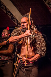 北岛，新西兰-2017 年 5 月 17 日： 高见毛利传统刺青位脸部的男人身穿传统服装，手里拿着一根木棍，玉木文化村，罗托鲁阿毛利人文化