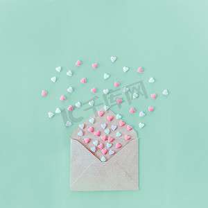 多色糖果糖心飞出工艺纸信封上的淡绿色的背景。情人节。爱的概念。礼物, 给情人的留言。文本的空间。方形格式