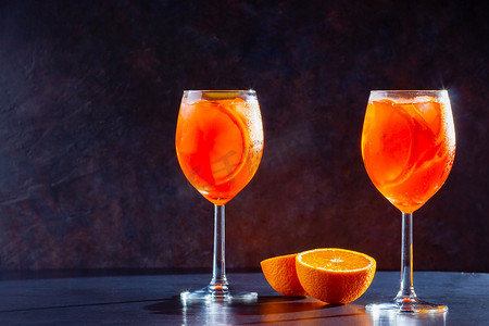 Aperol spritz鸡尾酒深色背景。两杯带有橙子片的开胃酒.夏天的鸡尾酒在杯子里。复制空间