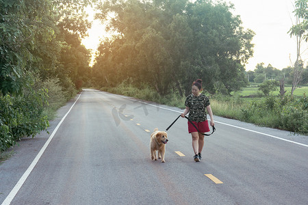 彩绘金毛摄影照片_亚洲女人带着她的金毛猎犬走在公共道路上
