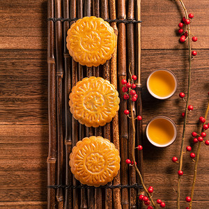 中秋节背景摄影照片_中国传统糕点月饼月饼与茶杯在竹盘上的木背景中秋节，顶视图，平铺.