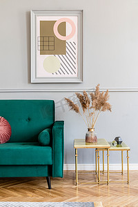 时尚典雅的公寓内部客厅，配有绿色天鹅绒咖啡桌、金色咖啡桌、鲜花和别致的配饰。在灰墙上模拟绘画框架。豪华家居装饰.
