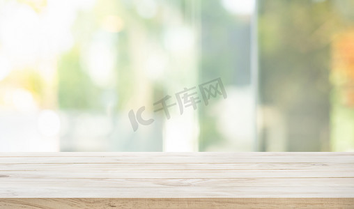 清澈的木桌顶部，从窗口看模糊的抽象绿色花园。用于蒙太奇产品的展示或设计关键的视觉布局