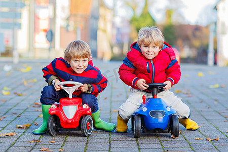两个小孩子男孩在玩玩具汽车，在户外