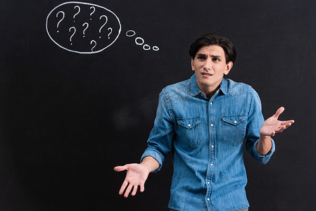 stressed young man with question marks in thought bubble on blackboard