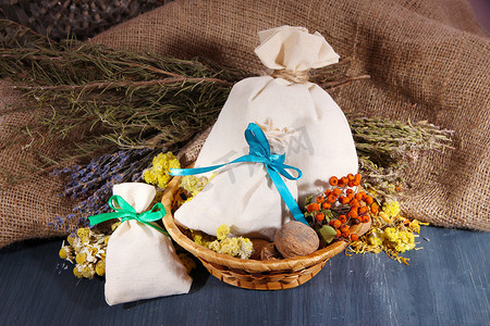 纺织干花、 草药和木制的桌子，麻布背景上的浆果香囊袋