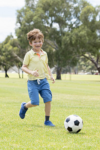 小孩子7或8岁享受快乐踢足球足球在草市公园田野奔跑和踢球兴奋的童年运动激情