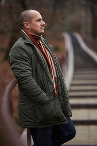 Portrait of a mature man in dark green winter coat in the park