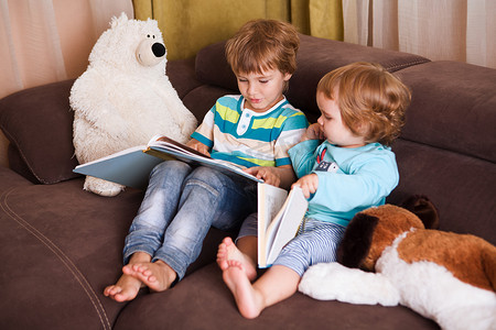 看书距离摄影照片_可爱的男孩和他的妹妹在家里一起看书。在家学习、远距离学习